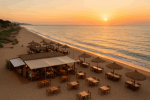 Vista aérea de un chiringuito en la playa del Maresme al atardecer con sombrillas y mesas junto al mar