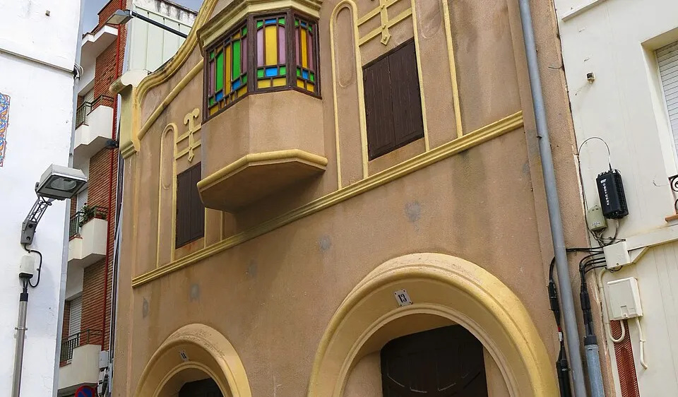 Casa modernista en el centro de Premià de Mar con tribuna de vidrieras y detalles arquitectónicos color mostaza