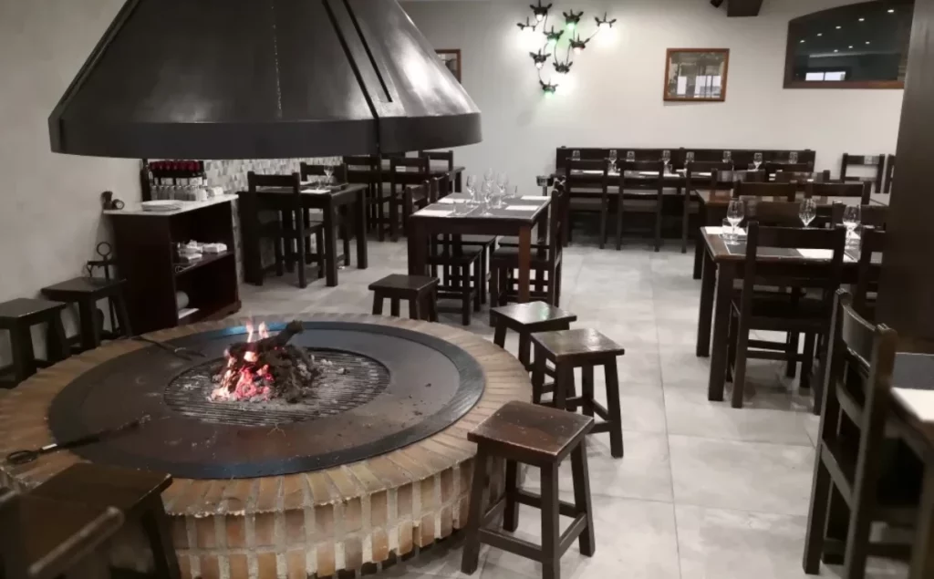 Interior de restaurante en Alella La Vinicola con parrilla central y zona de mesas, representando la experiencia gastronómica en restaurantes en Alella con cocina mediterránea y ambiente tradicional.
